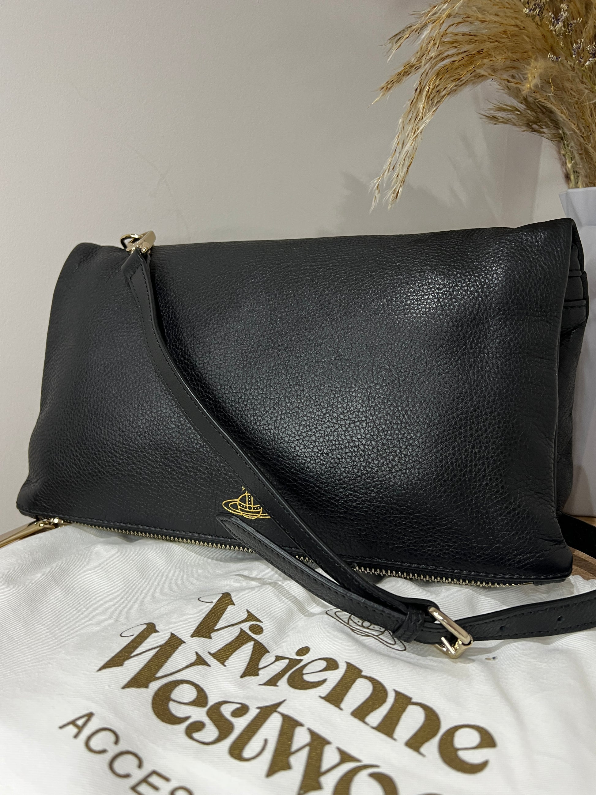 Black leather handbag with gold zipper on a light gray background